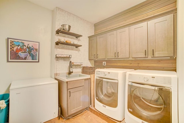 clothes washing area with washer and dryer, cabinet space, and a sink