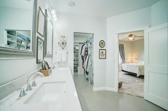 full bath with a textured ceiling, a walk in closet, a sink, and ensuite bathroom