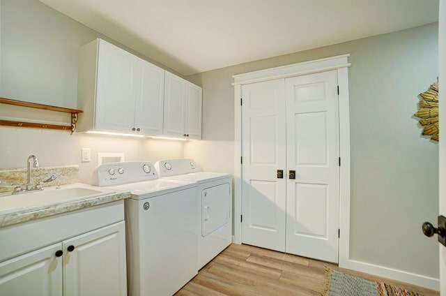 laundry room featuring a sink, cabinet space, light wood finished floors, and washer and dryer