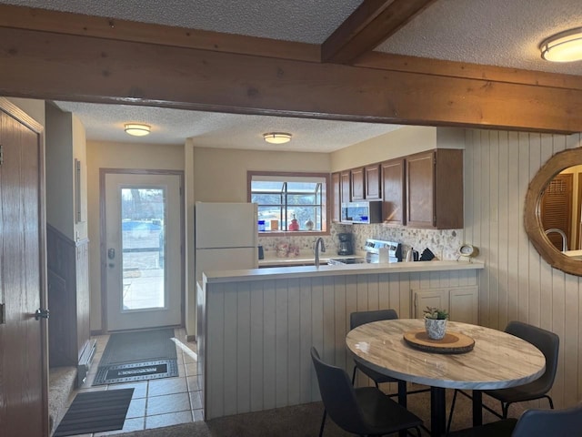 kitchen with a textured ceiling, a peninsula, light countertops, and stainless steel appliances