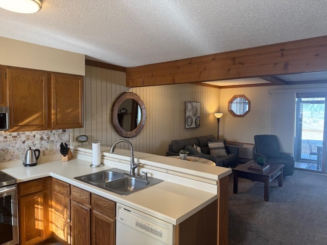 kitchen with a peninsula, a sink, stainless steel appliances, light countertops, and open floor plan