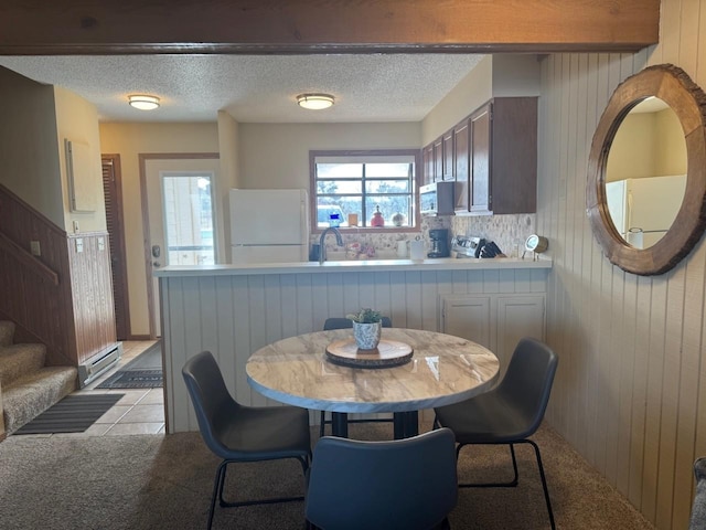 dining space featuring wooden walls, a textured ceiling, light tile patterned flooring, and stairs