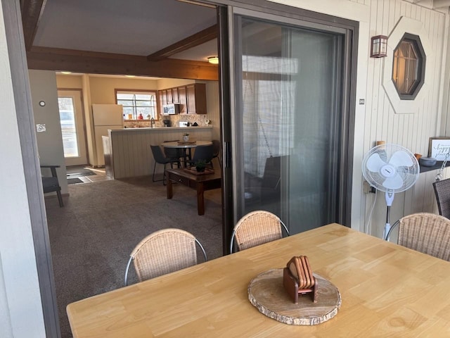 carpeted dining room with beamed ceiling and a sink