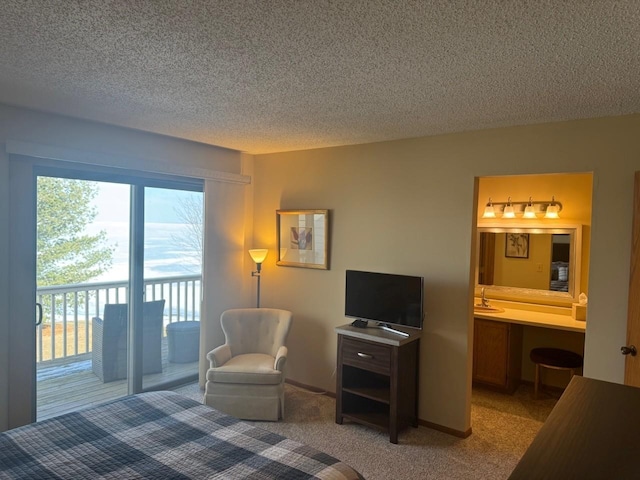 bedroom featuring a textured ceiling, connected bathroom, light colored carpet, access to exterior, and built in study area