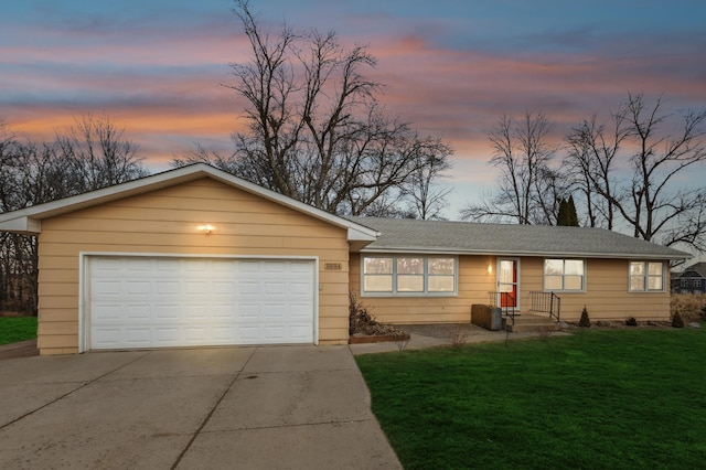 ranch-style home featuring a garage, a lawn, driveway, and a shingled roof