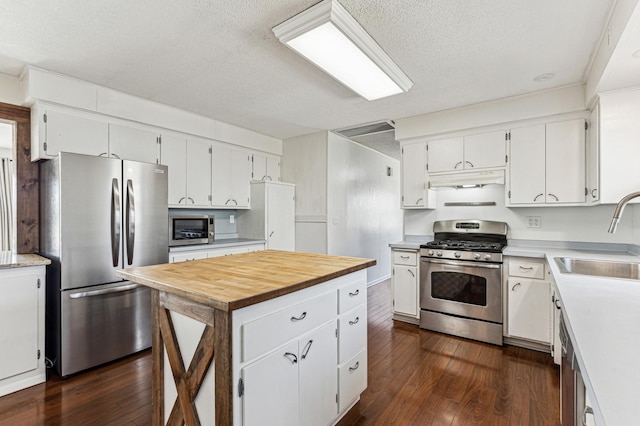 kitchen with stainless steel appliances, dark wood-type flooring, a sink, and white cabinetry