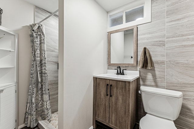 full bathroom featuring toilet, a stall shower, tile walls, and vanity