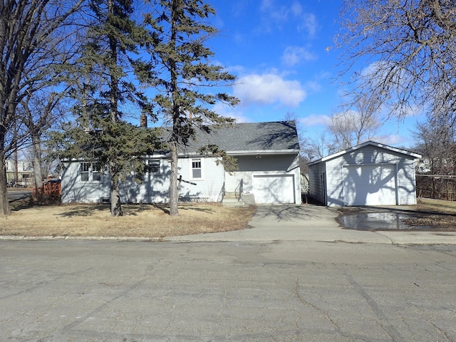 view of front of property with a shingled roof, driveway, and an outdoor structure