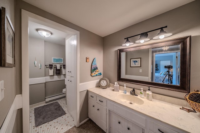 bathroom featuring a baseboard heating unit, toilet, and vanity