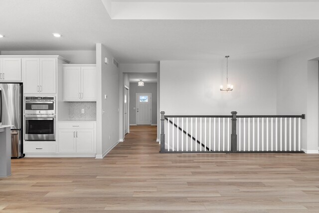 10720 Harbor Ln N, Maple Grove, MN 55369 - kitchen with appliances with stainless steel finishes, baseboards, light wood-type flooring, and white cabinetry