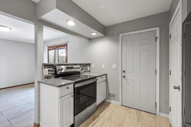 kitchen featuring electric range, visible vents, baseboards, white cabinetry, and backsplash