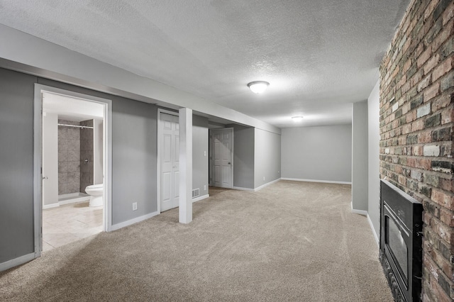 finished below grade area with visible vents, baseboards, a textured ceiling, carpet flooring, and a fireplace