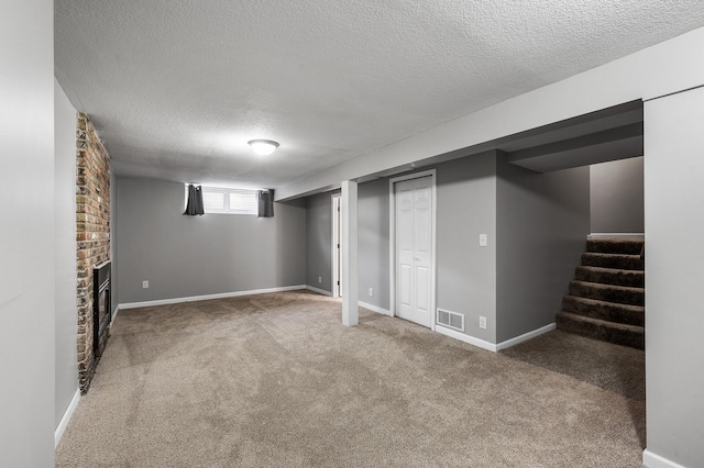 basement with visible vents, stairway, carpet, a textured ceiling, and a fireplace