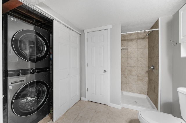 laundry area featuring stacked washer and dryer, laundry area, and light tile patterned flooring