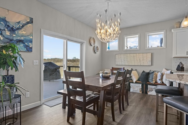 dining space featuring baseboards, a textured ceiling, an inviting chandelier, and wood finished floors