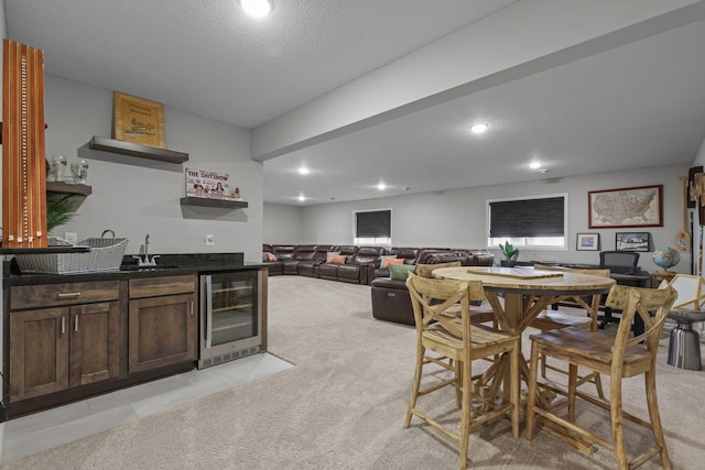 dining room with a textured ceiling, recessed lighting, beverage cooler, light carpet, and indoor wet bar