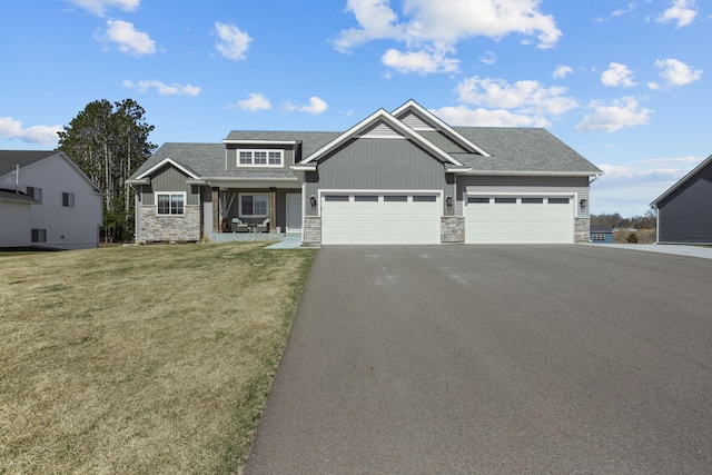 craftsman inspired home featuring aphalt driveway, a shingled roof, an attached garage, a front yard, and stone siding