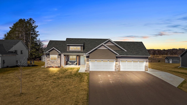 view of front of property featuring a garage, stone siding, a yard, and concrete driveway