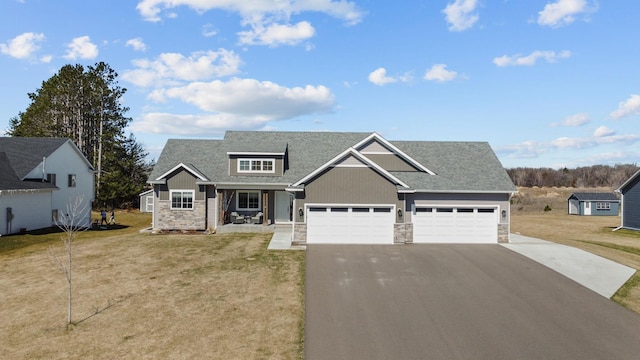 view of front of house featuring a garage, stone siding, a front yard, and driveway