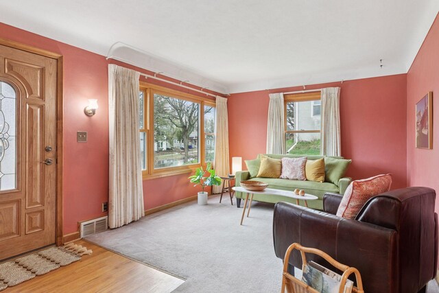 living area featuring wood finished floors, visible vents, plenty of natural light, and baseboards