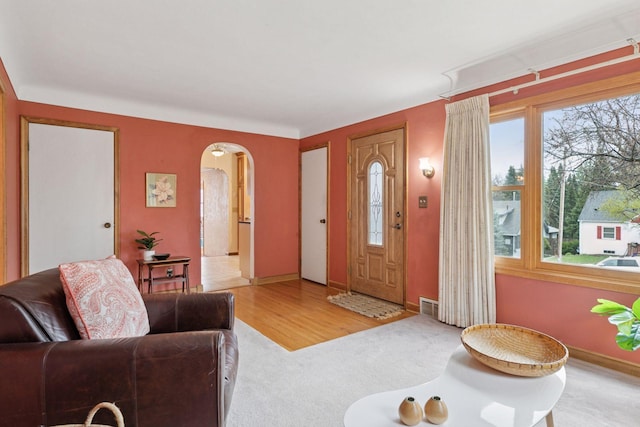 entrance foyer featuring baseboards, visible vents, arched walkways, and carpet floors