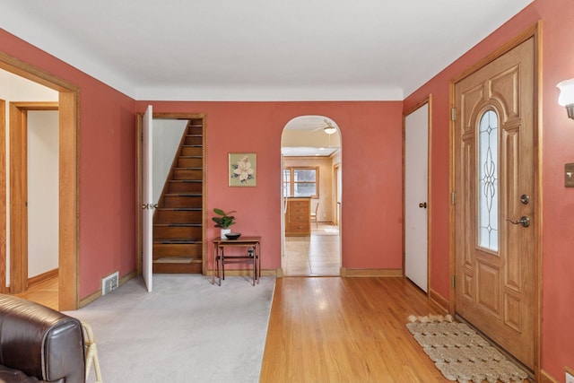 entrance foyer with arched walkways, visible vents, light wood-style flooring, and baseboards