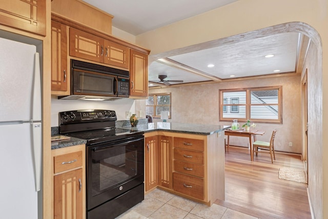 kitchen featuring dark stone counters, brown cabinetry, black appliances, a ceiling fan, and a peninsula