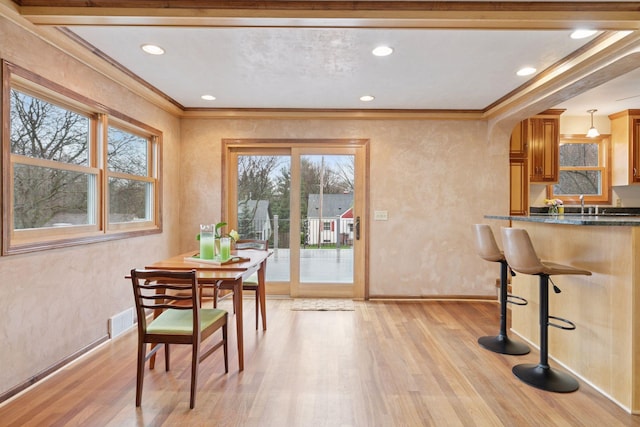 dining room with baseboards, ornamental molding, and light wood-style flooring