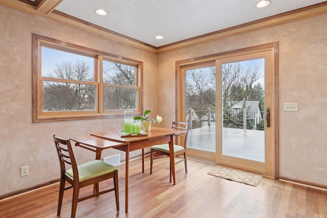 dining space featuring light wood finished floors, plenty of natural light, ornamental molding, and baseboards