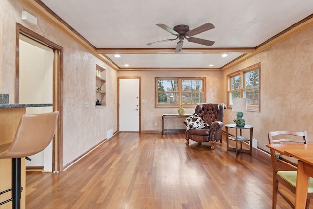 living area featuring wood finished floors, ceiling fan, crown molding, and visible vents