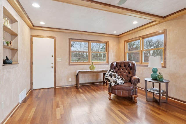 living area featuring visible vents, wood finished floors, and ornamental molding