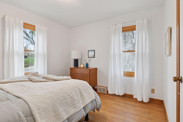 bedroom featuring visible vents, light wood-style flooring, and baseboards