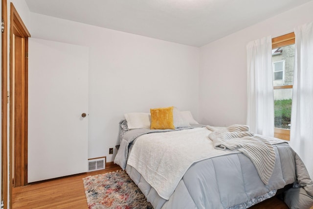 bedroom featuring baseboards, visible vents, multiple windows, and light wood-style flooring