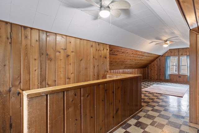 additional living space with tile patterned floors, wooden walls, a ceiling fan, and lofted ceiling