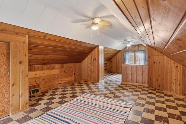 bonus room with lofted ceiling, wood walls, visible vents, ceiling fan, and tile patterned floors