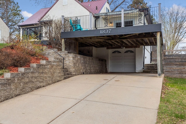 view of side of property with stairway, metal roof, concrete driveway, and an attached garage