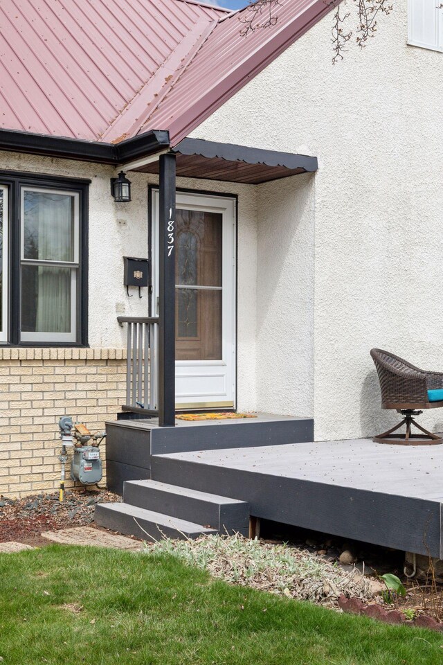 view of exterior entry featuring stucco siding and brick siding