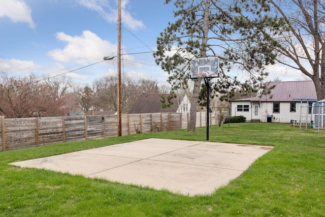 view of sport court featuring basketball court, fence, and a lawn