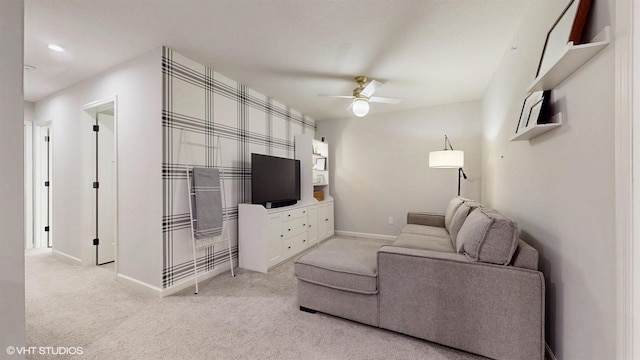 living room featuring baseboards, a ceiling fan, and light colored carpet