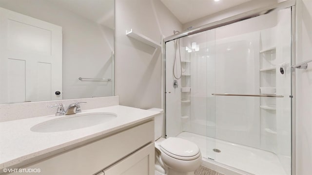 full bathroom featuring a stall shower, vanity, and toilet