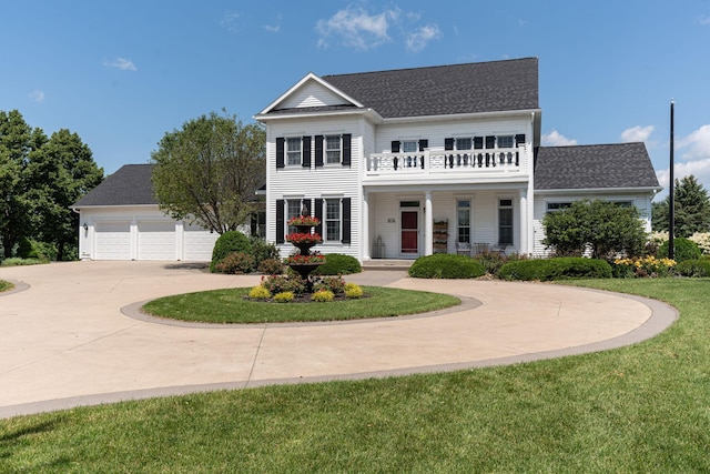 view of front of home with concrete driveway, a shingled roof, a front lawn, and a balcony