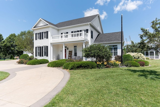 greek revival house with a balcony, a shingled roof, and a front lawn