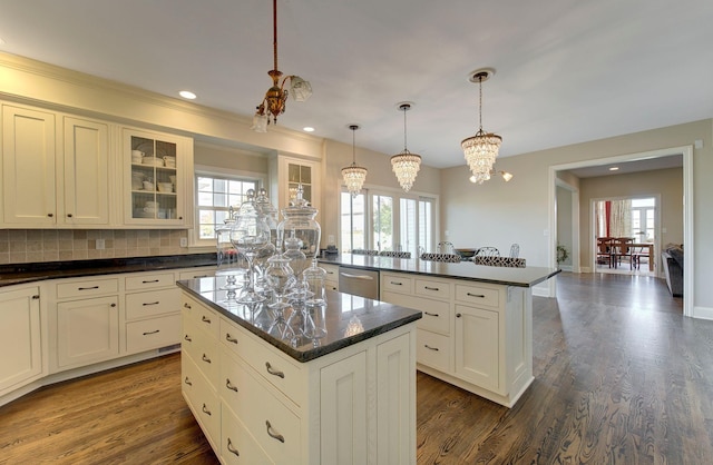 kitchen with stainless steel dishwasher, dark wood-type flooring, glass insert cabinets, a kitchen island, and a peninsula