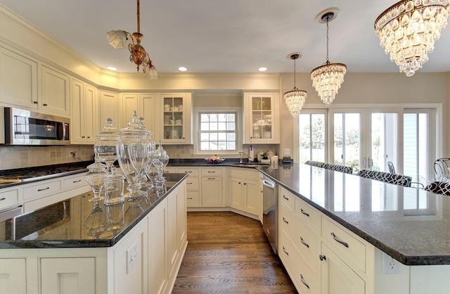 kitchen featuring dark wood-style floors, a kitchen island, appliances with stainless steel finishes, an inviting chandelier, and backsplash