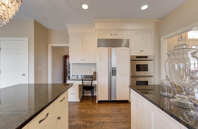 kitchen with dark wood-type flooring, stainless steel double oven, paneled built in fridge, and recessed lighting