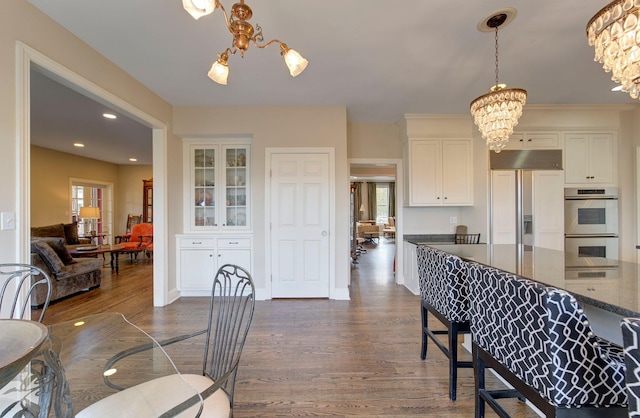 dining space featuring baseboards, dark wood-style flooring, recessed lighting, and a notable chandelier