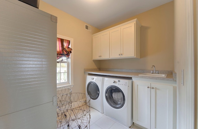 washroom featuring light tile patterned floors, a sink, visible vents, washer and dryer, and cabinet space