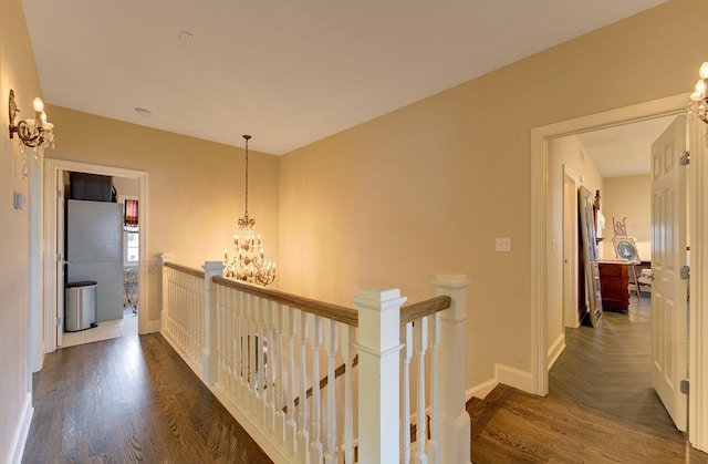 hall with a notable chandelier, baseboards, wood finished floors, and an upstairs landing