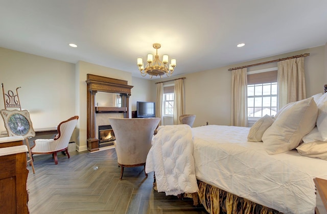 bedroom with a notable chandelier, baseboards, a glass covered fireplace, and recessed lighting