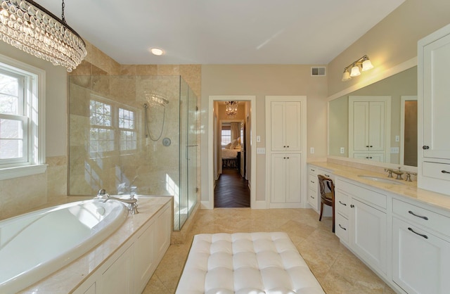 ensuite bathroom with visible vents, a shower stall, vanity, a chandelier, and a bath